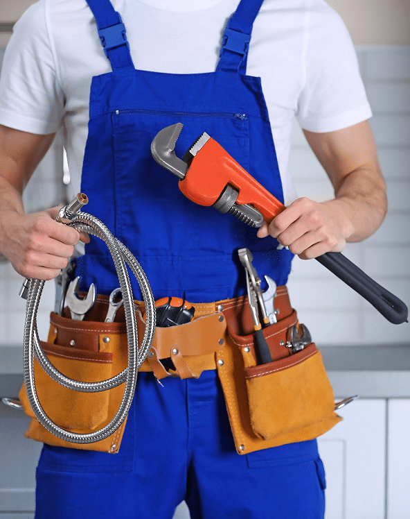 Plombier en salopette bleue tenant une clé à molette rouge et un flexible de douche. Ceinture à outils en cuir avec outils.