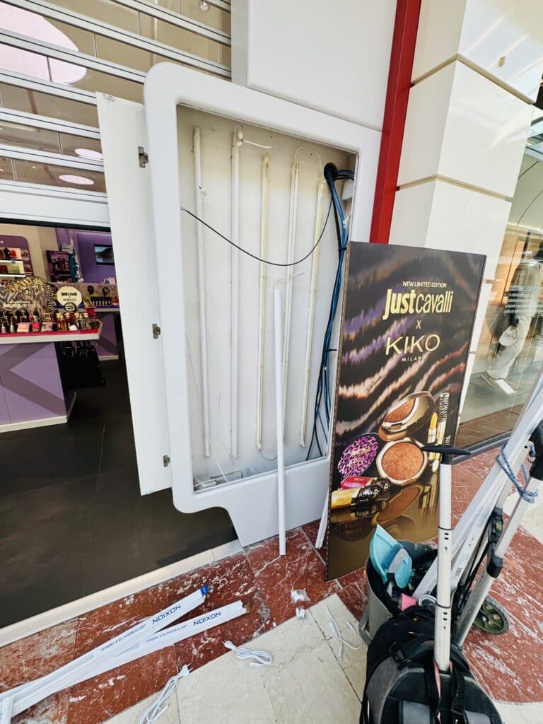 Installation de tubes LED Noxion dans un panneau Just Cavalli x KIKO Milano ouvert pour maintenance en boutique.