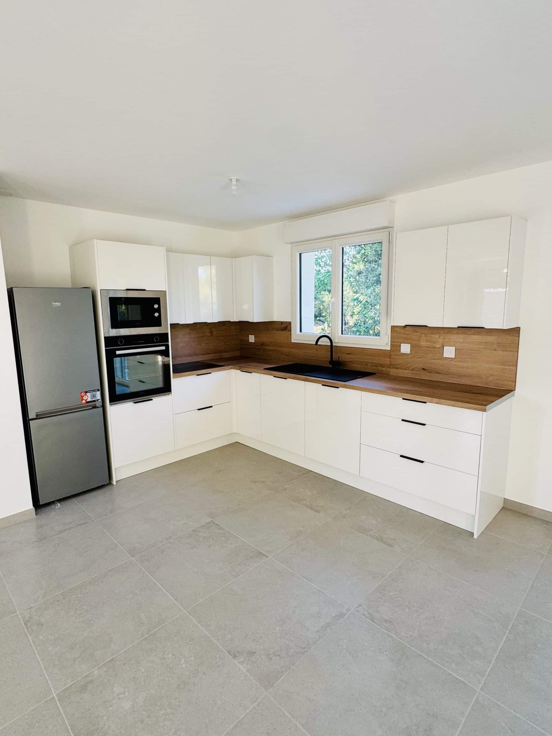 Cuisine moderne blanche et bois, électroménager Beko, plan de travail chêne, évier noir et carrelage gris.